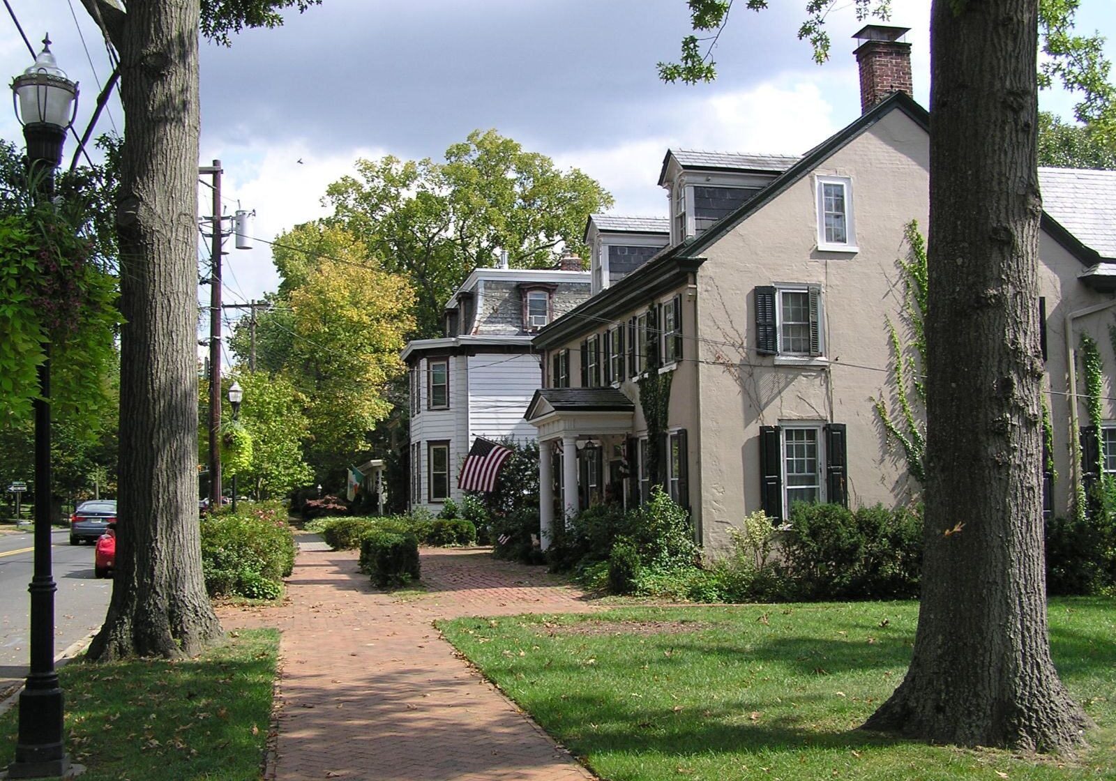 Tree-lined street in Moorestown with a traditional style house, sidewalk, and well-maintained lawn and landscaping.